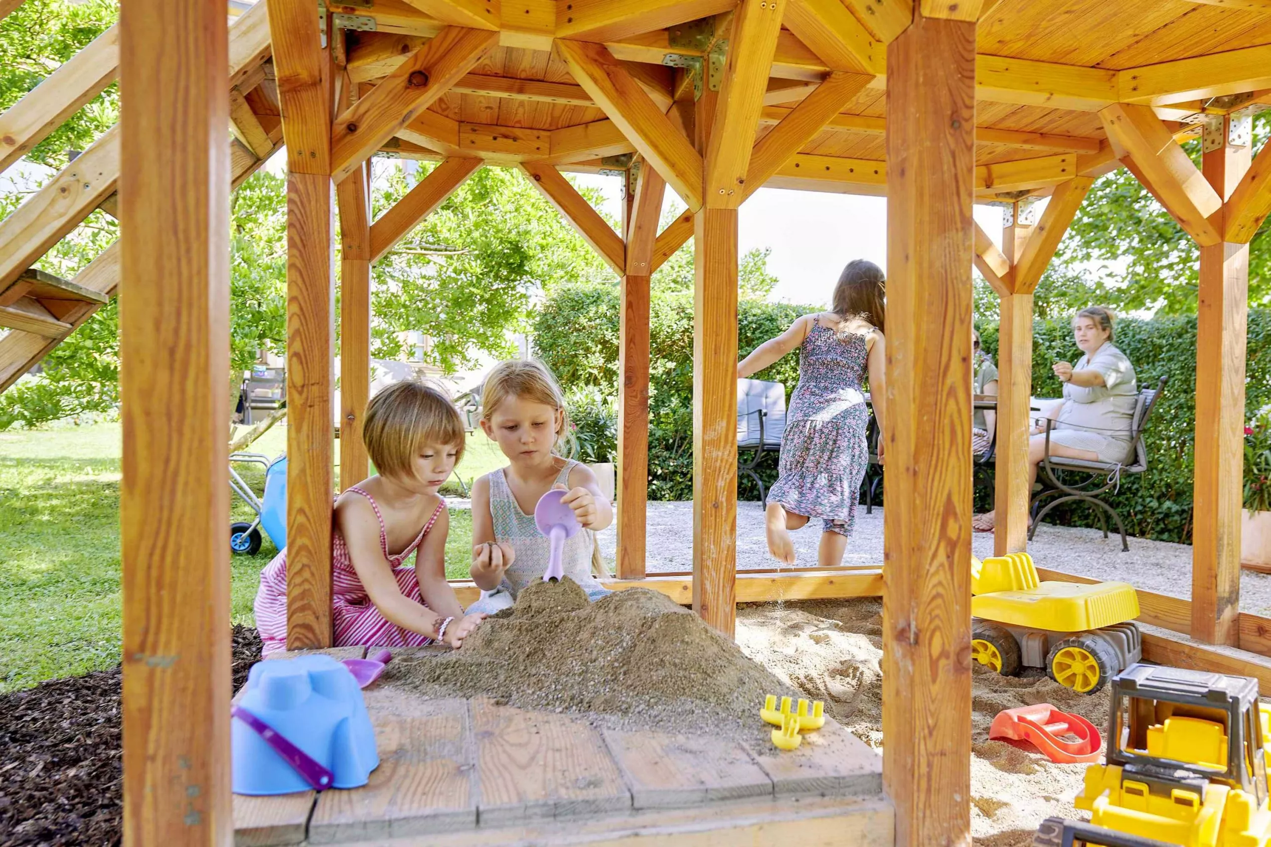 Überdachter Sandkasten Spielhaus am Spielplatz im Grünen mit Riesen-Trampolin